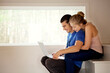 © Cavan Images - Happy couple using laptop computer while sitting on steps at home