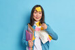 © WHstudio Leushin N - Pleased Asian woman office worker with pleased expression holds folders prepares research work makes reminding notes indicates directly at camera wears casual jumper isolated over blue background