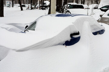 Wall Mural - Moscow, Russia. 13th February 2021. A blizzard covered the city. A blue car is completely covered under the snow