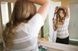 © Cavan Images - Rear view of woman curling hair with machine at home