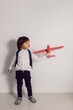 © saulich84 - boy child in a white shirt and jeans flies on a red airplane toy at the white wall of the house