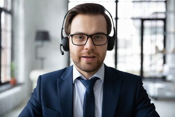 Wall Mural - close up headshot portrait of male ceo or director in headphones talk speak on video call in office 