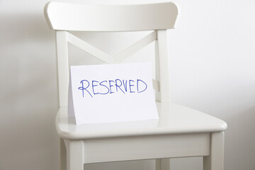 empty white chair with reserved sign