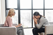 © Vadim Pastuh - Girl at a psychologist's appointment,talking about hard period,holding her hands near the head,crying,blonde woman writing down notes,the psychologist with glasses is listening attentively,advising