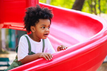 cute african american little kid boy having fun while playing on the playground in the daytime in su