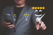 © Dilok - Businessman using smartphone and pushing smile button for the best evaluation , customer satisfaction concept.