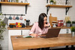 © Юлия Буракова - A woman works in the office remotely from home in the kitchen, sitting at the computer. Distance learning online education and work. Girl student prepares for exams.