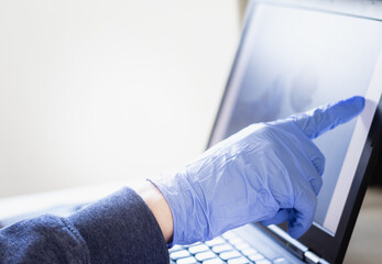 blue gloves touches a laptop screen, working from home in the Corona