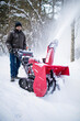 © Cavan Images - Happy elderly man snow blowing his driveway.