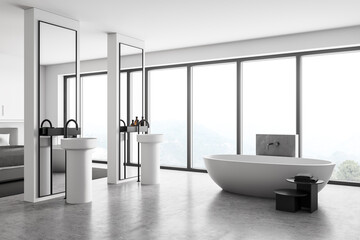 Grey and white bedroom with sinks and bathtub near window