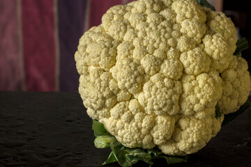 Fresh organic cauliflower on black table.