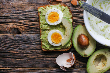 Wall Mural - Toast with mashed avocado and eggs on messy rustic wooden table