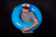 © Denis - Handsome guy sailor and lifebuoy. Blue inflatable circle. Black background.