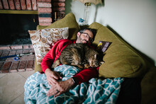 Man Asleep On A Couch With A Brown Tabby Cat Asleep On Him