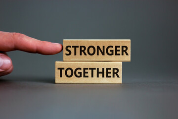 Wall Mural - Stronger together symbol. Concept words 'stronger together' on wooden blocks on a beautiful grey background. Businessman hand. Business, motivational and stronger together concept.