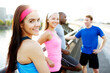 © Cavan Images - Portrait of female athletes standing with male friends on footbridge against clear sky in city