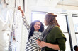 © Cavan Images - Smiling businesswoman looking at female colleague while standing by bulletin board in office