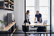 © Cavan Images - Businessman discussing with colleague in creative office seen through window