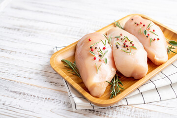 Chicken fillet with herbs and spices on white wooden table close up. Chicken meat with ingredients for cooking. Copy space.