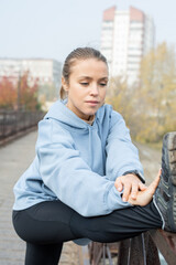 Wall Mural - Young active sportswoman standing on bridge during physical exercise for legs