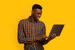 © Prostock-studio - Freelance Work. Portrait Of Smiling African Guy Using Laptop Over Yellow Background