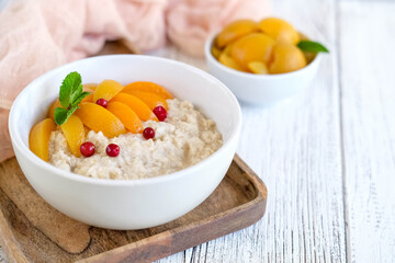 Wall Mural - Oatmeal with apricots on tray and wooden background. Fresh and healthy breakfast