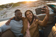 © Wavebreak Media - Diverse couple sitting in a convertible car and taking a selfie