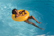 Mixed race woman sunbathing on inflatable in swimming pool