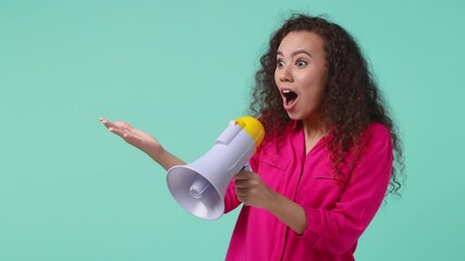 Canvas Print - Shocked crazy young african american woman 20s in pink shirt isolated on blue turquoise background studio. People lifestyle concept. Put hand on cheek spreading arms looking aside scream in megaphone