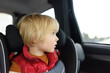 © Maria Sbytova - Portrait of a preschooler boy sitting in a car seat and wearing a belt. Сhild is looking out the window of a car during a family trip. Safety of children in transport.