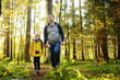 © Maria Sbytova - Cute schoolchild and his mature father hiking together and exploring nature. Little boy with his dad spend quality family time together in the sunny summer forest.