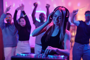 Sticker - Pretty girl with long blond hair touching headphones while mixing sounds