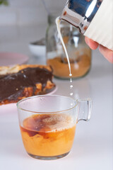 Cup of Tea falling splash of milk, on white background with chocolate puff pastry, whole grain panela. white brick wall background