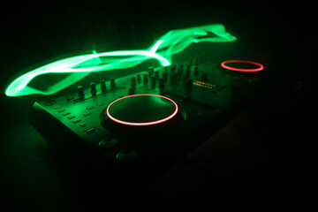 Wall Mural - DJ console deejay-mixing desk in dark with colorful light. Mixer equipment entertainment DJ station.