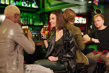 Wall Mural - Young smiling brunette woman in casualwear having beer with her boyfriend