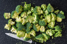 Fresh Cut Up Florets Of Broccoli Ready For Cooking, Large Black Cutting Board, Paring Knife

