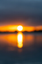 Intense Golden Sunrise Intentionally Defocused For Abstract Or Background Effect Between Layer Of Dark Cloudy Sky And Sea