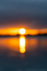 Sticker - Intense golden sunrise intentionally defocused for abstract or background effect between layer of dark cloudy sky and sea