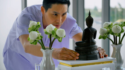 A Buddhist man taking a Buddha image to worship at home.