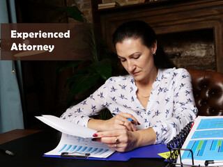 Wall Mural -  Experienced Attorney inscription. Female office workers with yellow shirt holding and writing documents on office desk