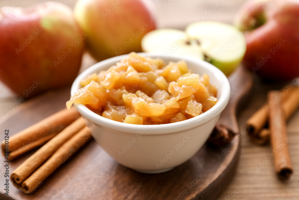 Bowl with sweet apple jam and cinnamon on wooden background