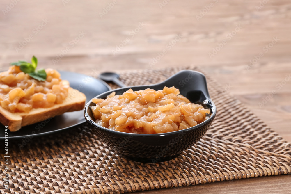 Bowl with sweet apple jam and toasts on wooden background