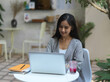 © bongkarn - Businesswoman working on laptop on coffee table with beverage in cafe