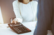 © Iryna - Accountant checking financial statement or counting by calculator income for tax form, hands close-up. Business woman sitting and working with colleague at the desk in office. Audit concept