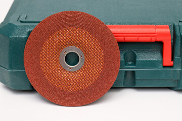 Wall Mural - Abrasive wheel, grinding wheel orange on the background of the green toolbox. Abrasive materials, discs, tools close-up