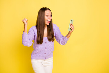 Poster - Photo of young girl happy positive smile look cellphone celebrate win victory fists hands isolated over yellow color background