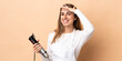 © luismolinero - Woman using hand blender over isolated background looking far away with hand to look something