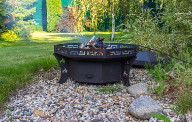  Wood is burning  in a metal fire bowl. Used for cooking,   warming up on a cold evening in the open air.