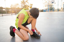 Teenager With Basketball, Tying Shoes At Street Basketball Court
