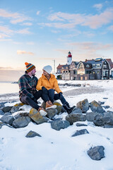 Wall Mural - couple men and woman by the lighthouse of Urk Netherlands during winter in the snow. Winter weather in the Netherlands by Urk